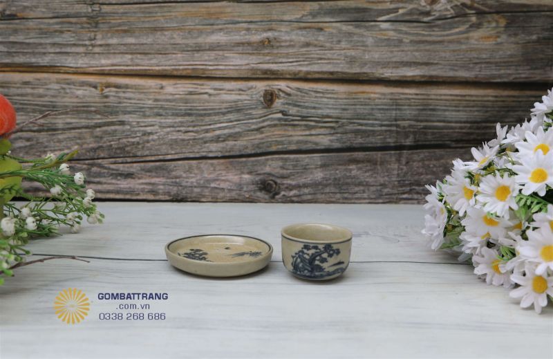 Chén trà men rạn cổ nhỏ nhắn, men lam cổ điển, đường nét vẽ tay mềm mại thể hiện cảnh núi non và tùng cúc trúc mai, mang lại cảm giác thư thái trong từng ngụm trà