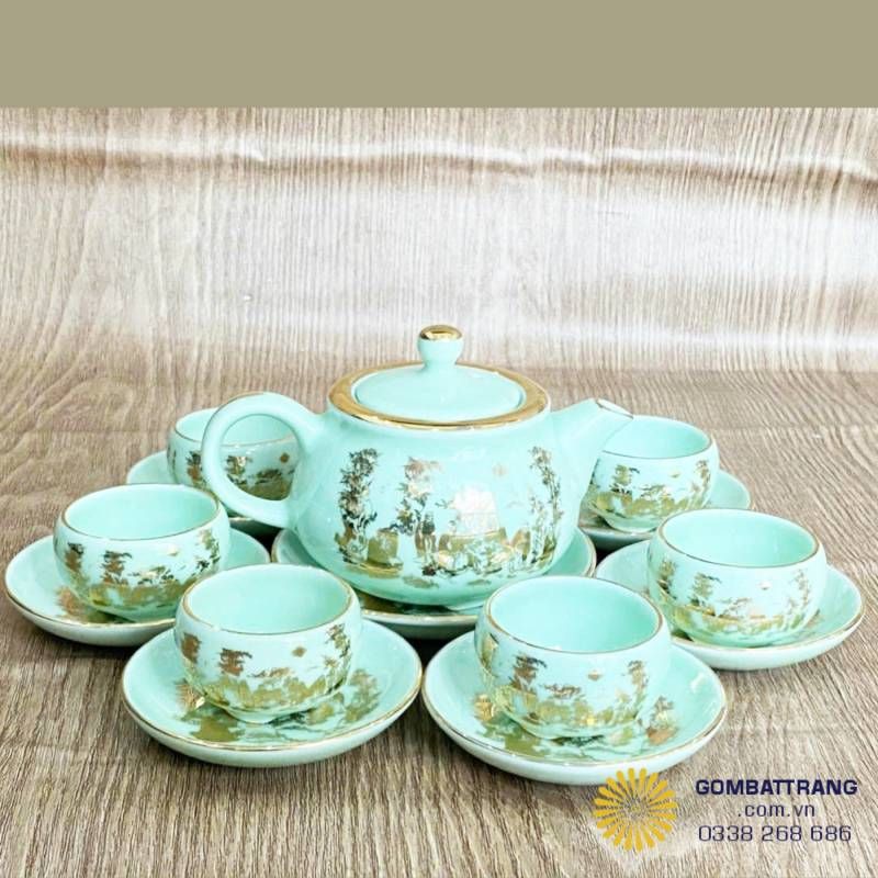 Toàn bộ bộ ấm chén – Hiển thị tổng thể bộ ấm chén Ngọc Trúc Lâm với ấm, 6 chén và đĩa lót, ánh sáng làm nổi bật men xanh ngọc và chi tiết dát vàng.