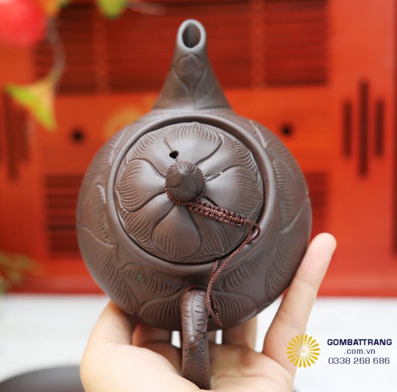 Nắp ấm khắc nổi hoa sen nở, gân cánh mềm mại, ánh men bắt sáng nhẹ, tôn vẻ tinh tế thủ công.