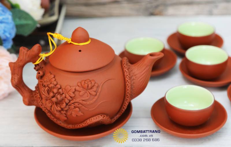 Một góc nhìn gần, chiếc ấm tròn căng, hoa khắc nổi mềm mại. Tay cầm và vòi ấm nối liền tự nhiên, dáng chắc mà thanh, vừa mắt, vừa lòng người uống trà.
