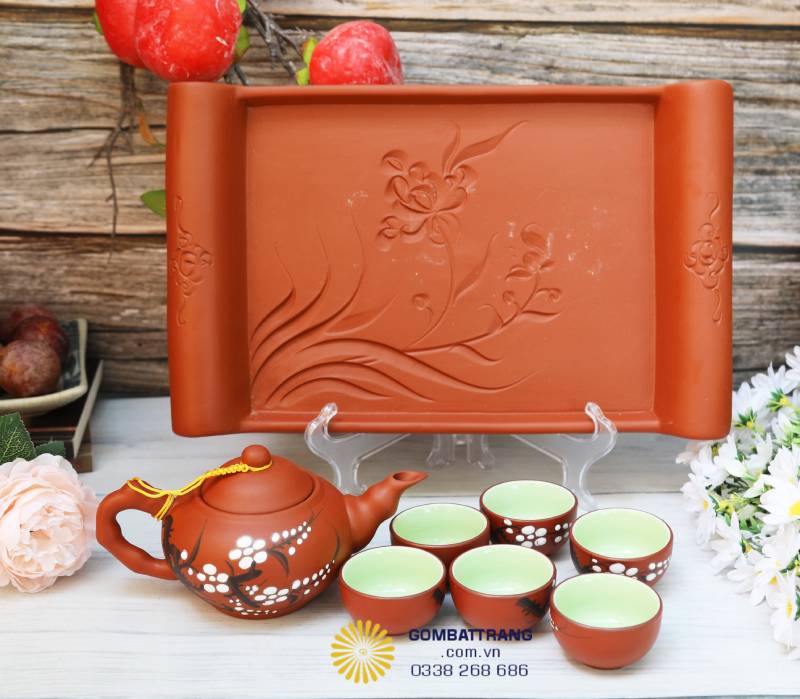 Bộ ấm đặt trên khay chữ nhật khắc hoa mai nổi, biểu trưng cho sự may mắn, thanh khiết – rất được ưa chuộng làm quà tặng Tết, tân gia.