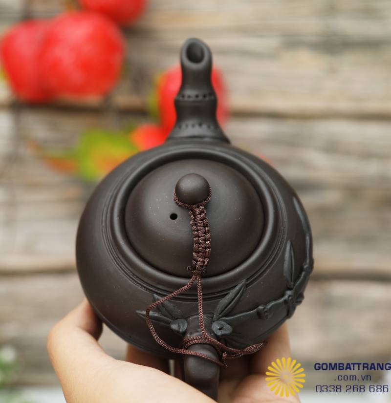 Góc nhìn cận nắp ấm, nơi sợi dây đỏ buộc khẽ như một nét duyên — mỗi chi tiết nhỏ đều mang dấu tay của người thợ, tinh tế đến từng nhịp khắc.