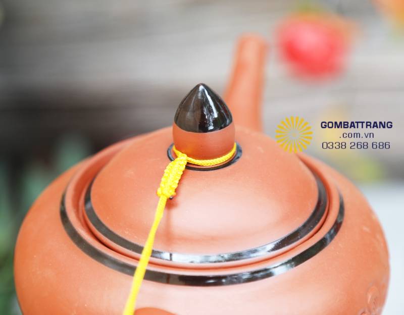 Nắp ấm chóp đen thanh lịch, dây vàng nối liền biểu tượng cho sự vững bền, may mắn và tinh tế trong từng chi tiết.