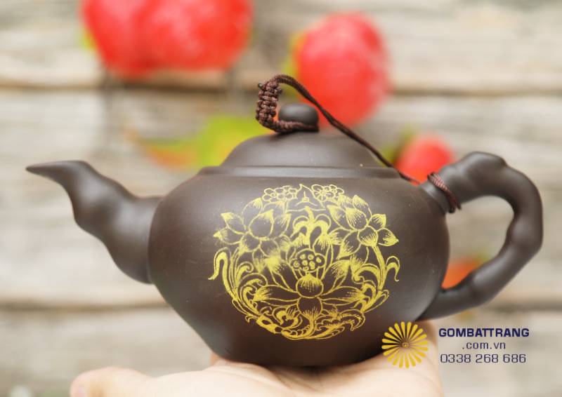 Họa tiết sen vàng được khắc thủ công, từng nét mềm uyển chuyển như cánh sen vừa hé nở. Lớp men vàng ánh lên trong ánh sáng, biểu trưng cho tinh thần thuần khiết và phú quý.