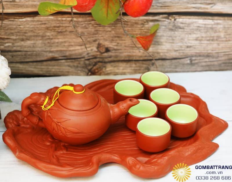 Bộ ấm chén đỏ nâu đặt trên khay men nâu giả gỗ, dễ vệ sinh, tăng độ sang trọng cho không gian trưng bày.