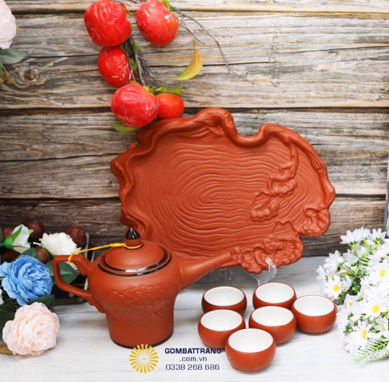 Bộ ấm chén trên khay gốm thân gỗ độc đáo, kết hợp hoa văn tự nhiên mang lại cảm giác mộc mạc và tinh tế.