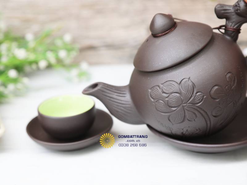 Ấm và chén đặt cạnh nhau trong sắc sáng tự nhiên, làm nổi bật tương phản giữa men ngọc bên trong và màu nâu đất bên ngoài – biểu trưng cho sự hài hòa giữa thô và tinh, đất và trời.