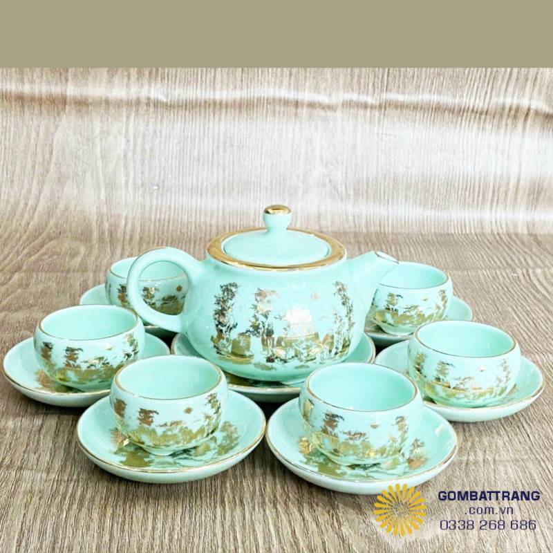 Toàn bộ bộ ấm chén – Hiển thị tổng thể bộ ấm chén Ngọc Trúc Lâm với ấm, 6 chén và đĩa lót, ánh sáng làm nổi bật men xanh ngọc và chi tiết dát vàng.