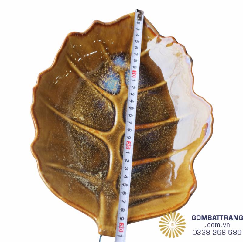 Cận cảnh đĩa hình lá gốm Bát Tràng với đường gân nổi tinh xảo trên nền men vàng hổ phách độc đáo.