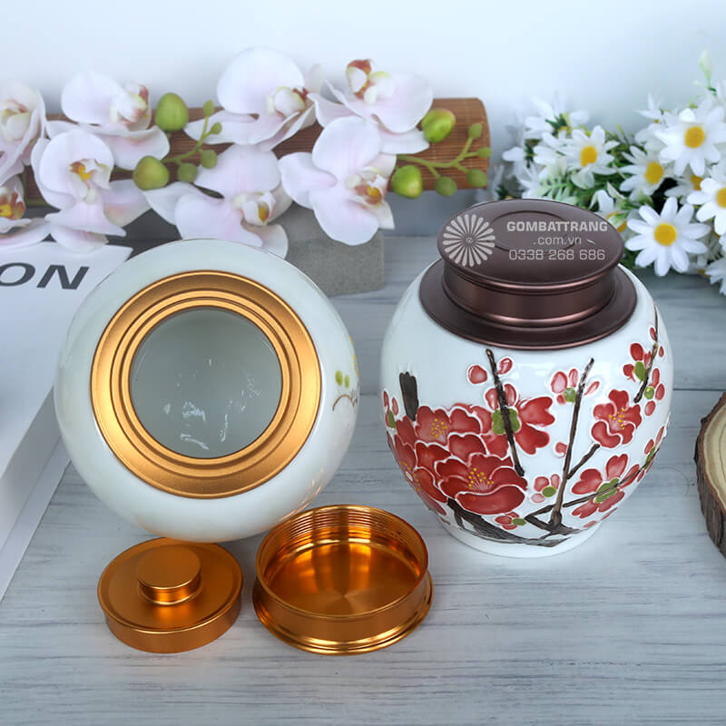 Hộp đựng trà bằng gốm có nắp màu vàng đồng, trang trí họa tiết nhẹ nhàng màu xanh nhạt, toát lên vẻ thanh tao, nhã nhặn