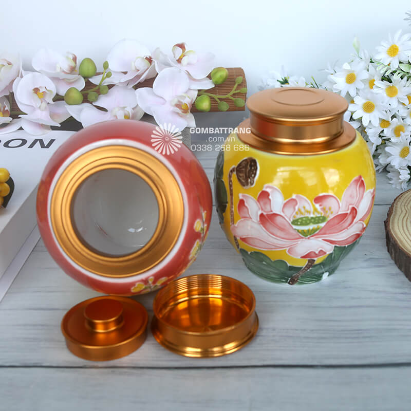 Hũ màu vàng tươi được trang trí hoa sen hồng – biểu tượng cho sự thanh cao, thuần khiết và an lành trong phong thủy