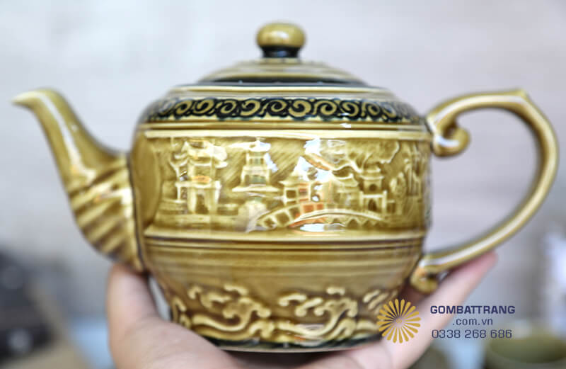 Xung quanh thân ấm và chén là hình ảnh ngôi chùa, đình làng và cây cầu được khắc nổi 3D sinh động